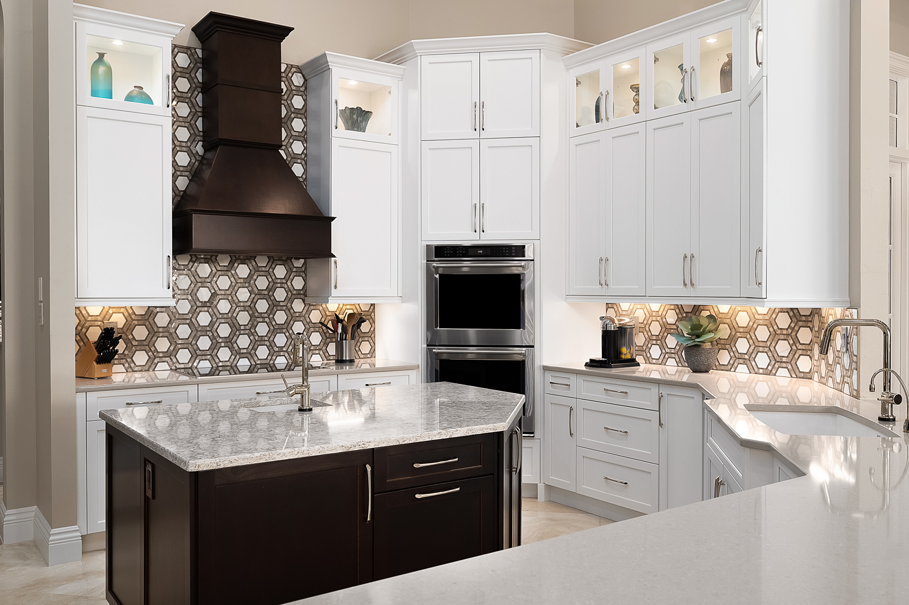 Updated kitchen has white cabinets, island in espresso finish, quartz countertops and decorative backsplash tile